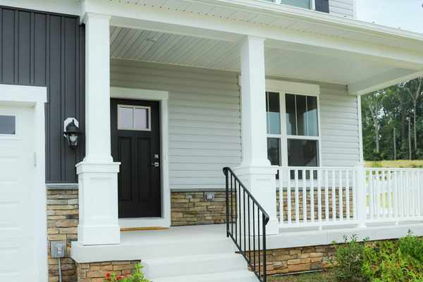 Two-story home exterior with light gray horizontal siding, dark vertical accent siding, and a covered front porch