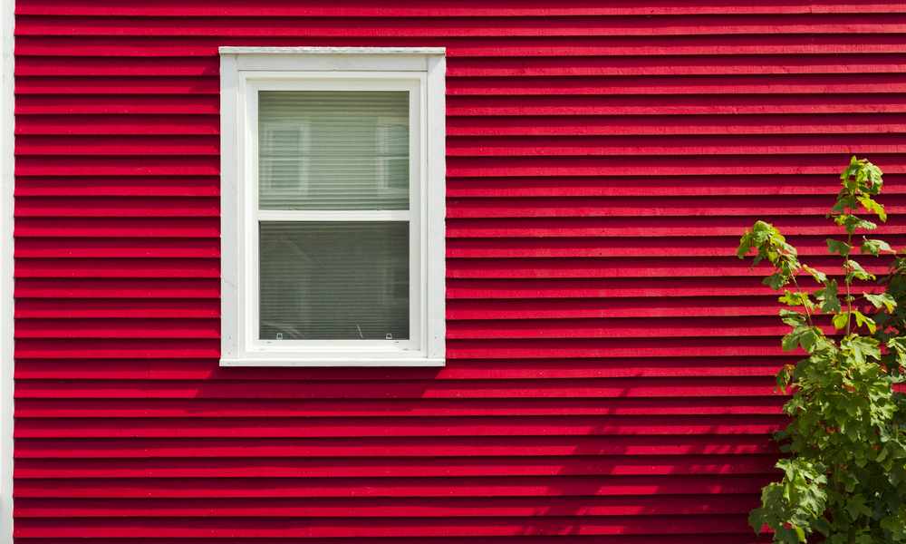 Close-up of red horizontal siding and a window on a home exterior