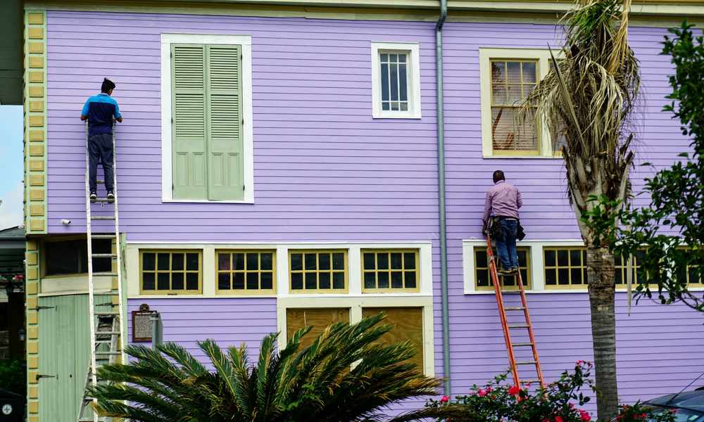 Contractors on ladders working on a home's exterior wall