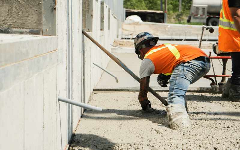 Two workers in high-visibility vests working on an exterior wall